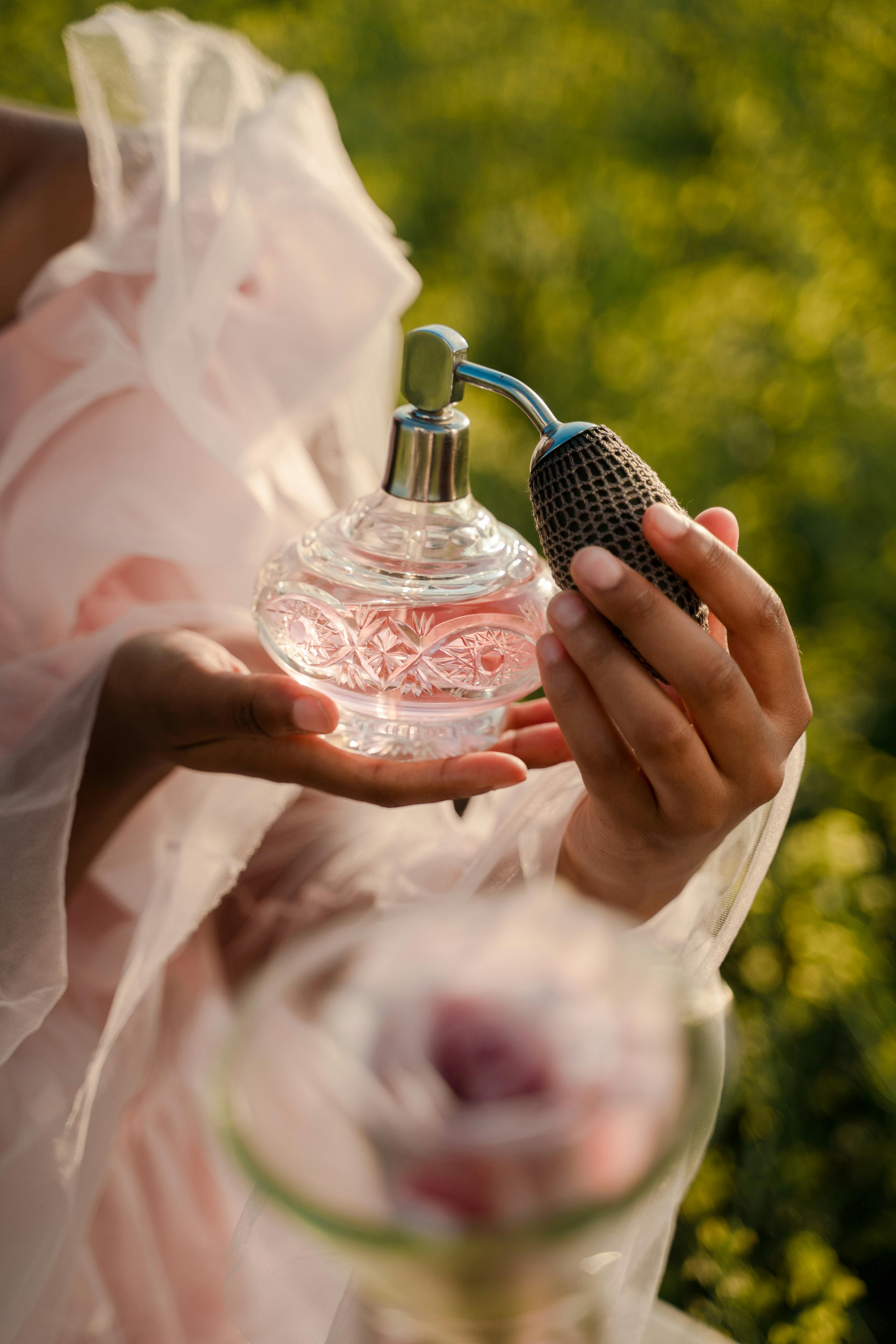 Hands holding a beautiful crystal pink perfume bottle outdoors, representing M Luxury Perfumes authentic Arabian fragrance collection